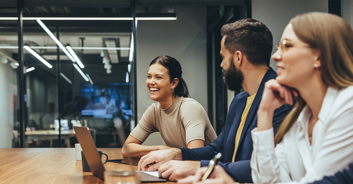 Young people in a glass office meeting room smiling