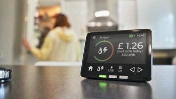 A smart meter placed on a kitchen worktop showing important information on energy usage